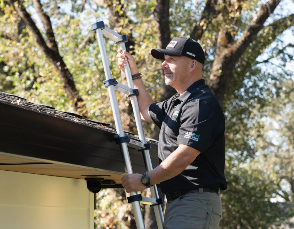 Good Life Inspections technician on a ladder inspecting a home's roofline and gutter